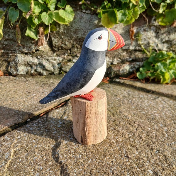 Stunningly realistic handcarved and individually painted Puffin.        Perched on a wooden stand that measures 12cm from beak to tail.