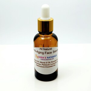 May include: A brown glass bottle with a gold lid and a white dropper top. The bottle is labeled "All Natural Anti-Aging Face Serum" and "NANA'S NATURALS Products Made with Love". The label also lists the ingredients: Jojoba Oil, Vitamin E Oil, Rosehip Oil, Frankincense, Patchouli, Lavender and Helichrysum Essential Oils.