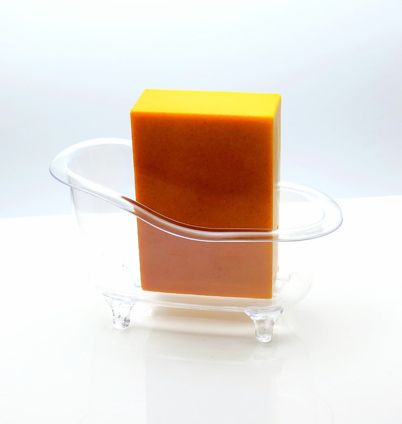 May include: A clear plastic bathtub-shaped soap dish with a bright yellow bar of soap inside.