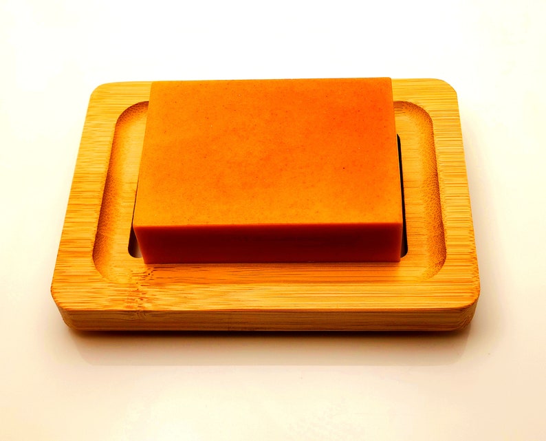 May include: A rectangular orange soap bar on a wooden soap dish.