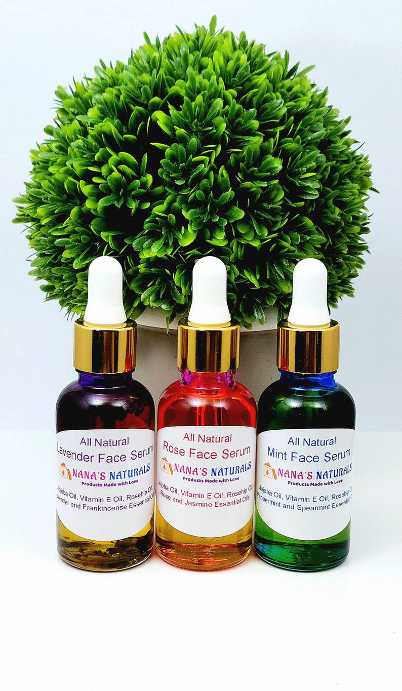 May include: Three glass bottles with gold lids and droppers containing face serums. The bottles are labeled "All Natural Lavender Face Serum", "All Natural Rose Face Serum", and "All Natural Mint Face Serum". Each bottle has a label with the company name "NANA'S NATURALS" and the phrase "Products Made with Love".