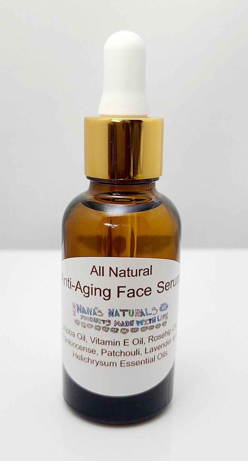 May include: A glass bottle with a gold lid and a white dropper top. The bottle is labeled "All Natural Anti-Aging Face Serum" and lists the ingredients: Jojoba Oil, Vitamin E Oil, Rosehip Oil, Frankincense, Patchouli, Lavender and Helichrysum Essential Oils.