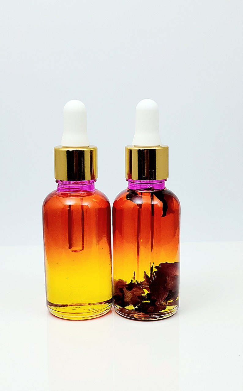 May include: Two amber glass bottles with gold lids and white droppers. The bottles are filled with a yellow liquid and contain dried flower petals.