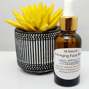 May include: A small amber glass bottle with a gold lid and a white dropper. The bottle is labeled "All Natural Anti-Aging Face Serum" and lists the ingredients: Jojoba Oil, Vitamin E Oil, Rosehip Oil, Frankincense, Patchouli, Lavender, and Helichrysum Essential Oils.