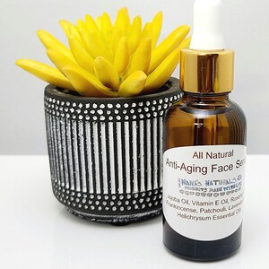 May include: A glass bottle with a gold lid and dropper filled with a clear liquid. The bottle is labeled "All Natural Anti-Aging Face Serum" and lists ingredients including jojoba oil, vitamin E oil, rosehip oil, frankincense, patchouli, lavender, and helichrysum essential oils.