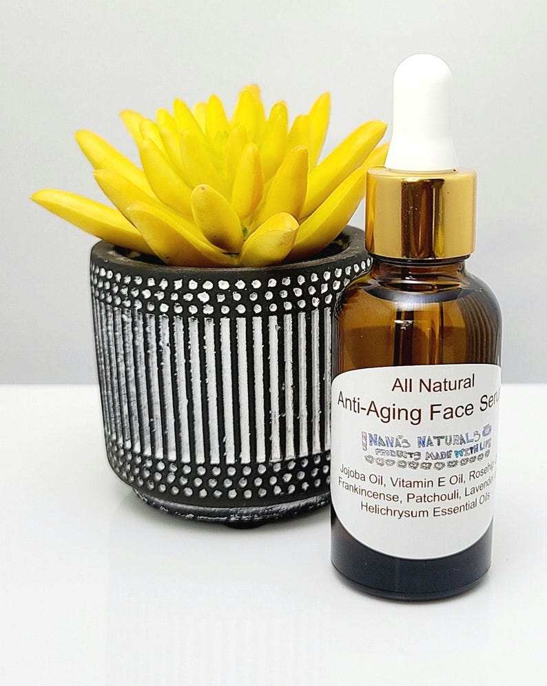 May include: A glass bottle with a gold lid and dropper filled with a clear liquid. The bottle is labeled "All Natural Anti-Aging Face Serum" and lists ingredients including jojoba oil, vitamin E oil, rosehip oil, frankincense, patchouli, lavender, and helichrysum essential oils.