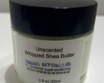 May include: A white jar with a black lid containing unscented whipped shea butter. The label reads "Unscented Whipped Shea Butter", "Nanas Naturals", "Products Made With Love", and "2 fl oz / 60ml".