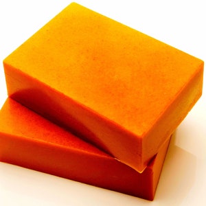 May include: Two rectangular bars of orange soap stacked on top of each other.