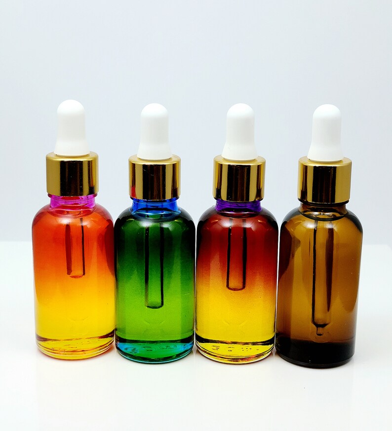 May include: Four glass bottles with gold caps and white droppers. The bottles are filled with a clear liquid and have a gradient color effect. The colors are orange, green, yellow, and brown.
