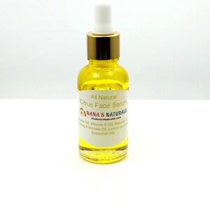 May include: A glass bottle of all-natural citrus face serum with a gold lid and dropper. The label reads "All Natural Citrus Face Serum" and "NANA'S NATURALS Products Made with Love". The ingredients listed are jojoba oil, vitamin E oil, rosehip oil, evening primrose oil, lemon and lime essential oils.