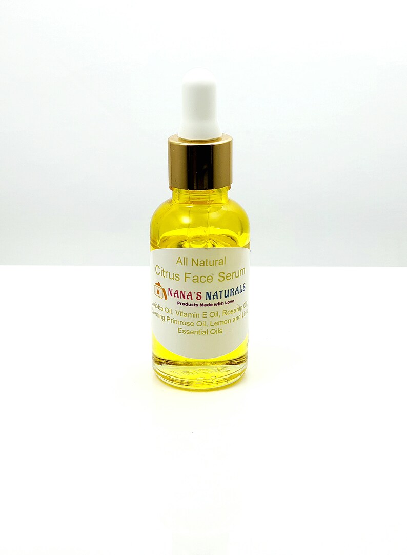 May include: A glass bottle of all-natural citrus face serum with a gold lid and dropper. The label reads "All Natural Citrus Face Serum" and "NANA'S NATURALS Products Made with Love". The ingredients listed are jojoba oil, vitamin E oil, rosehip oil, evening primrose oil, lemon and lime essential oils.