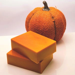 May include: Two orange bars of soap stacked on top of each other. The soap is in the shape of a rectangle. A burlap pumpkin is in the background.