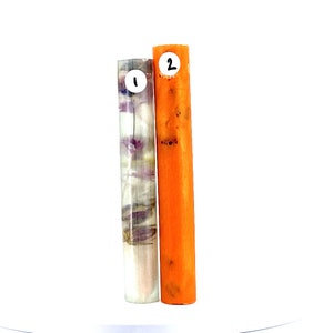 May include: Two cylindrical objects. One is translucent with purple floral inclusions, labeled "1". The other is solid orange, labeled "2". Both stand upright against a white background. The objects appear to be decorative or functional.