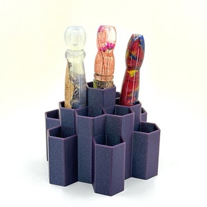 May include: A purple hexagonal organizer with three colorful glass pipes. The pipes are made of clear glass with embedded flowers and swirls of color.