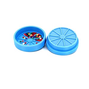 May include: A blue plastic container with a lid, divided into 12 sections. The container is filled with colorful plastic beads.