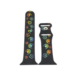 May include: Black watch band with a colorful paw print and flower pattern. The band is made of a flexible material and features a stainless steel buckle. The paw prints and flowers are in shades of yellow, orange, green, and blue.