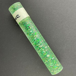 May include: A green and white glitter filled tube with a white label that says "like" on it.