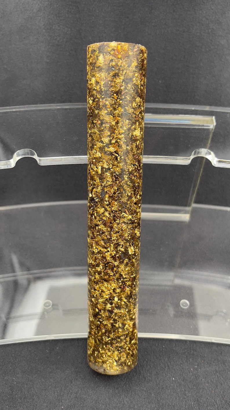 May include: A long, cylindrical, dark brown and gold pen blank with gold flecks throughout.