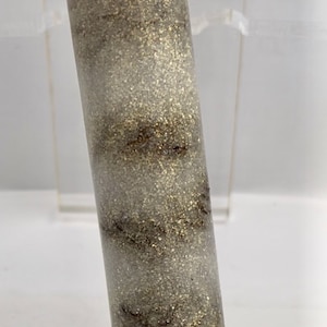 May include: A white and gold glitter tube with brown swirls. The tube is made of clear resin and has a smooth, shiny finish.