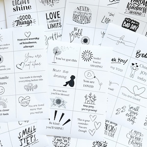 Puede incluir: Una colección de tarjetas blancas con texto e ilustraciones en negro. Las tarjetas presentan citas y frases inspiradoras como "Never stop dreaming", "You are loved" y "Be kind, you'll shine!" Las tarjetas están dispuestas sobre una superficie blanca.