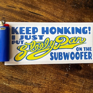 May include: White sticker with blue and yellow text that reads "Keep Honking! I Just Put "Skooly Dan" On The Subwoofer".