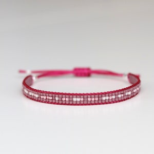 May include: A pink and white beaded bracelet with a sliding knot closure.