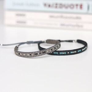 May include: Two beaded bracelets, one with silver and black beads, and the other with black and turquoise beads.