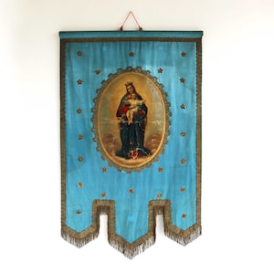 May include: A blue fabric banner with gold trim and a central oval image of a woman in a blue robe holding a child. The image is surrounded by a gold frame and a border of gold stars.