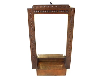 May include: A dark brown wooden mirror with a carved frame and a shelf underneath. The mirror is rectangular and has a simple design.