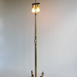 May include: A vintage brass floor lamp with two light bulbs. The lamp features a marble base with decorative dolphin accents. The lamp's height is approximately 60 inches.