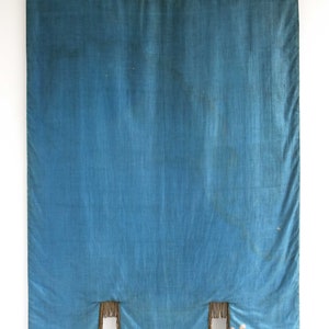 May include: A blue fabric banner with a fringed bottom edge. The banner is hanging from a wooden dowel rod with a red string.