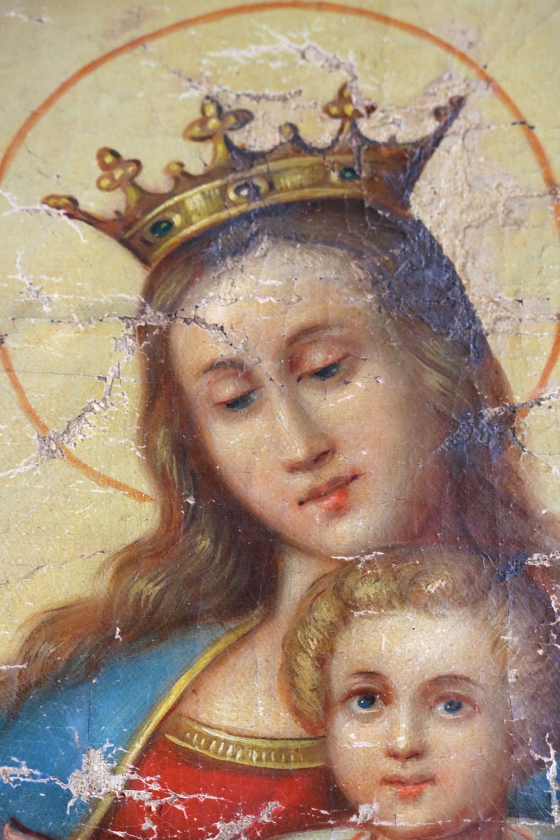 May include: A painting of a woman wearing a gold crown and a blue robe, holding a child. The woman has long, flowing hair and a gentle expression. The child is looking up at the woman with a sweet smile.