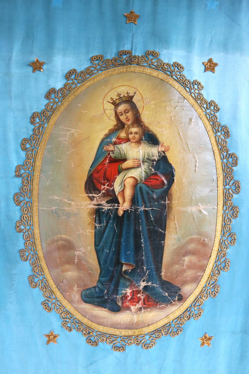 May include: A vintage painting of the Virgin Mary holding a baby Jesus. The painting is framed in a gold oval with a decorative border. The background is a light blue.
