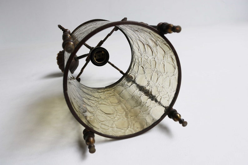 Pode incluir: Um abajur de estilo vintage com um design de vidro texturizado. O abajur &eacute; feito de vidro transparente com uma moldura de metal marrom e detalhes decorativos. O abajur &eacute; projetado para ser usado com uma l&acirc;mpada padr&atilde;o.