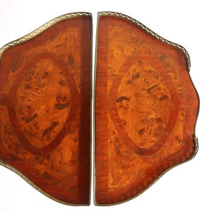 K&ouml;nnte beinhalten: Zwei passende Tischplatten aus Holz mit aufwendigen Marquetterie-Designs. Die Platten sind in einem satten Braun gehalten und haben einen dekorativen Messingrand.