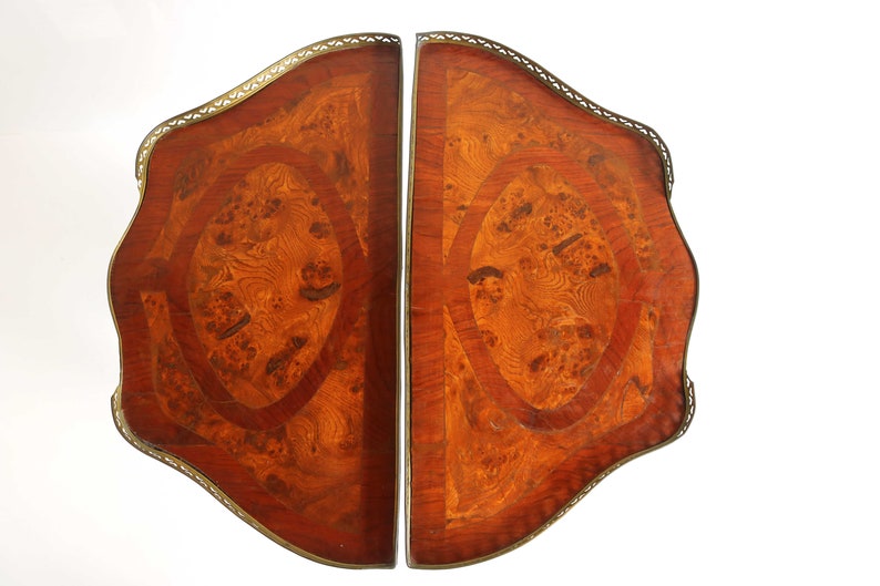 K&ouml;nnte beinhalten: Zwei passende Tischplatten aus Holz mit aufwendigen Marquetterie-Designs. Die Platten sind in einem satten Braun gehalten und haben einen dekorativen Messingrand.