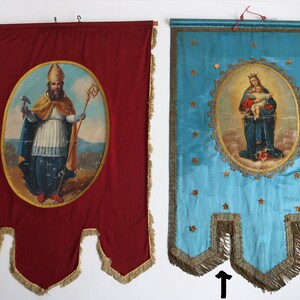 May include: Two vintage religious banners with gold trim and fringe. The banner on the left is red with a painting of a man in a bishop's robe holding a staff and a hammer. The banner on the right is blue with a painting of a woman holding a baby.