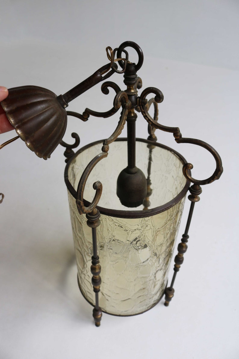 Pode incluir: Um candeeiro pendente vintage em lat&atilde;o e vidro com um abajur de vidro texturizado e trabalho de metal ornamentado. O candeeiro tem uma corrente e um gancho para pendurar.