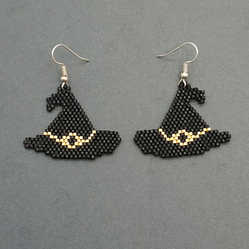 May include: A pair of black witch hat earrings with gold trim. The earrings are made of beads and have silver hooks.