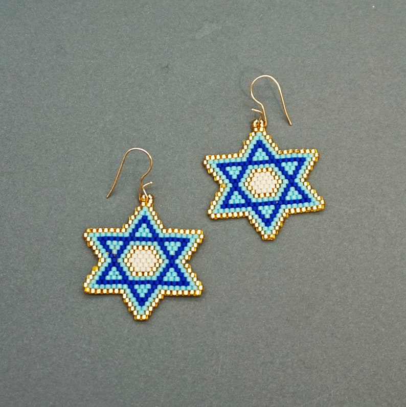 May include: A pair of gold earrings with blue and white beaded Star of David charms.