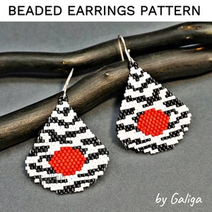 May include: A pair of black and white beaded earrings with a red circle in the center of each earring. The earrings are teardrop shaped and hang from silver hooks. The earrings are on a wooden background. "by Galiga" is written in the bottom right corner of the image.