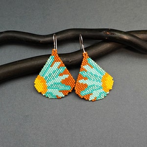 May include: A pair of teardrop-shaped earrings with a beaded design featuring a turquoise and orange flower pattern.