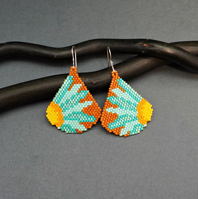 May include: A pair of teardrop-shaped earrings with a beaded design featuring a turquoise and orange flower pattern.