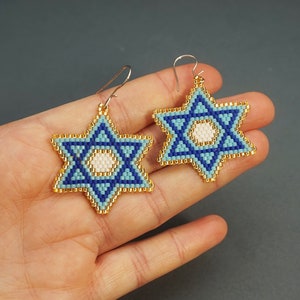 May include: A pair of blue and gold beaded Star of David earrings. The earrings are made with small blue and gold beads and have a white centre.