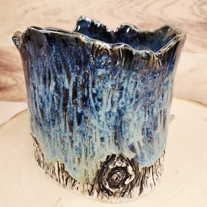 Peut inclure: Un vase en céramique fait à la main avec un design texturé en forme d'arbre. Le vase présente un mélange d'émail bleu et turquoise, avec un bord bleu foncé et une base sculptée détaillée. Le vase a une forme organique unique, idéale pour la décoration intérieure.