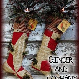 May include: Two red and white patchwork Christmas stockings with greenery and vintage Santa Claus ornaments hanging on a rustic wooden background. The stockings are decorated with red and white squares and have a vintage look. The text "Ginger and Company" is visible at the bottom of the image.
