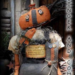 May include: A handmade pumpkin doll with a black and orange patchwork design. The doll is sitting on a rustic background with a sign that reads "When black cats prowl and pumpkins glean, may luck be yours on Halloween."