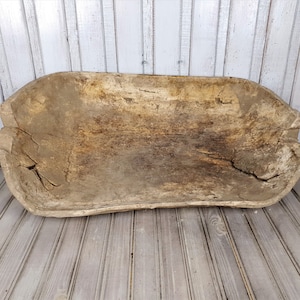 K&ouml;nnte beinhalten: Eine gro&szlig;e, rustikale Holz-Teigsch&uuml;ssel mit einer nat&uuml;rlichen, verwitterten Oberfl&auml;che. Die Sch&uuml;ssel ist oval geformt und hat einen breiten, flachen Boden.