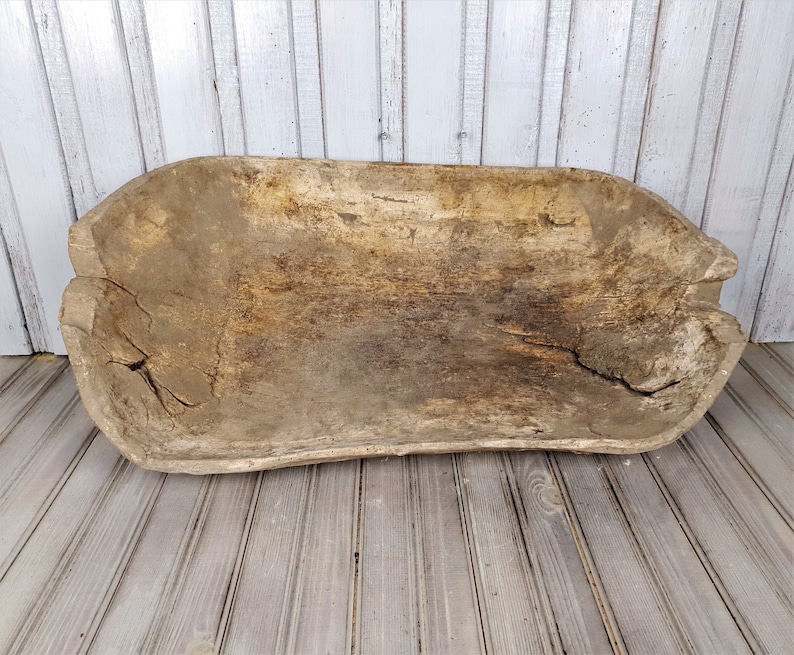 K&ouml;nnte beinhalten: Eine gro&szlig;e, rustikale Holz-Teigsch&uuml;ssel mit einer nat&uuml;rlichen, verwitterten Oberfl&auml;che. Die Sch&uuml;ssel ist oval geformt und hat einen breiten, flachen Boden.