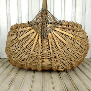 K&ouml;nnte beinhalten: Ein gro&szlig;er, geflochtener Korb aus nat&uuml;rlichen Materialien. Der Korb ist oval geformt und hat ein einzigartiges, f&auml;cherf&ouml;rmiges Design an der Oberseite. Der Korb ist braun und hat ein rustikales, vintage-m&auml;&szlig;iges Aussehen.